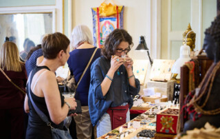 Visitatori allo stand di artigianato e benessere naturale a Officinalia