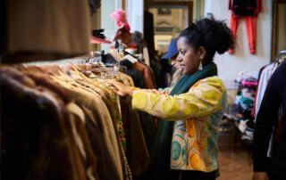 00023-Next-Vintage-Belgioioso-selezione-capi-stand Visitatrice seleziona capi d’abbigliamento vintage appesi su stand